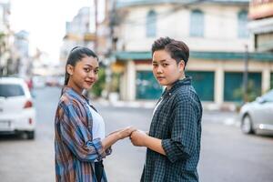 Two loving women standing and holding hands on the street. photo