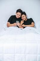 Two loving women sleeping and playing smartphones. photo