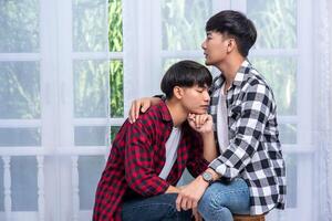 Two men who love each other hug and sit on a chair. photo