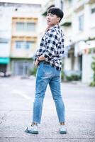 A young man in a striped shirt is standing on the street. photo