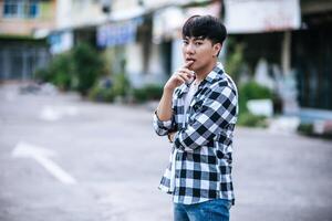 A young man in a striped shirt is standing on the street. photo