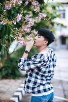 A young man in a striped shirt was standing on the roadside and holding the flower. photo