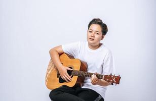 niña sentada en una silla y tocando la guitarra. foto