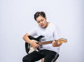 niña sentada en una silla y tocando la guitarra. foto