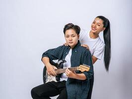 Two young women sat on a chair and played guitar. photo