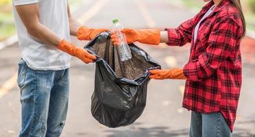 hombres y mujeres se ayudan mutuamente a recoger basura. foto