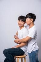 Two men who love each other hug and sit on a chair. photo