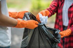 hombres y mujeres se ayudan mutuamente a recoger basura. foto
