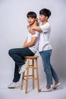Two men who love each other hug and sit on a chair. photo