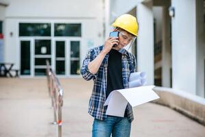 Architects hold floor plans and talk on the phone. photo