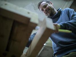 Carpenter sawing a piece of wood photo