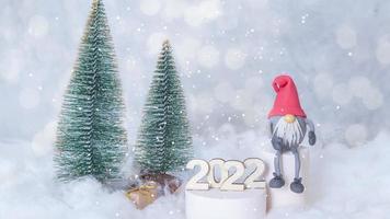 New Year 2022 animated background with flying snow on snowy background with gnome and Christmas trees photo