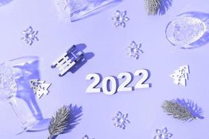 Festive new year flat lay with numbers 2022 and hard shadows with glasses and shiny decor photo