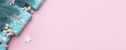 Banner de Navidad con regalos azules, bayas y pino sobre un fondo rosa con espacio de copia foto