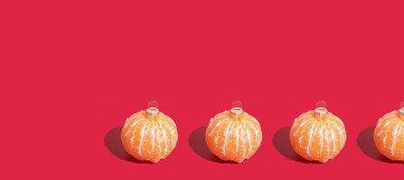 Banner with Mandarin pattern in the form of a Christmas tree toy on red background with copy space. Minimalistic christmas concept photo