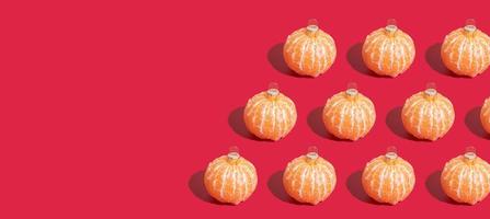 Banner with Mandarin pattern in the form of a Christmas tree toy on red background with copy space. Minimalistic christmas concept photo