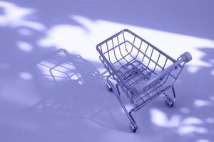 empty small shopping cart with nature hard shadows toned very peri coloe photo