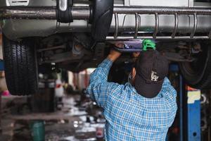 The mechanic is checking the undercarriage of the car. photo