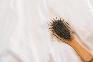 Peine y problema de pérdida de cabello sentado en la cama en el dormitorio foto