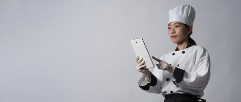 Asian woman chef holding smartphone or digital tablet and received order from online photo