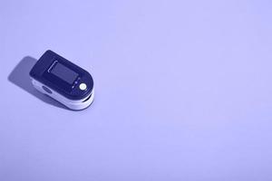 Portable pulse oximeter on a very peri background with a hard shadow. Control of oxygen in the lungs. view  above photo