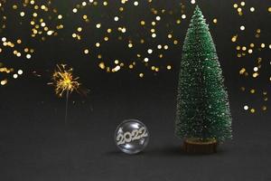 Christmas ball inside number tree covered with snow and sparklers on a black background. Concept for invitation postcard banner photo