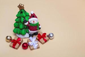 Christmas card. New Year tree with a snowman and gifts on a beige background. Close up, copy space photo