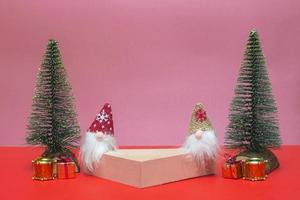Festive concept. On a colored background, a podium for cosmetics and various goods with gnomes, gifts and Christmas trees. Close up with copy space photo
