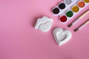 concepto de creatividad corazón decorativo y labios para pintar con pinturas. Pinturas, pinceles y decoración de corazón y labios sobre un fondo de color, vista superior de primer plano con espacio de copia foto