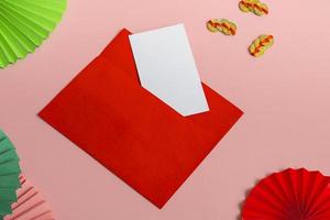 A red envelope with a blank card on a pink background with a paper fan and Chinese money. Close up, copy space photo