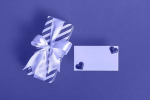 Gift box with blank card and hearts on a very peri background. Valentine's day concept. photo