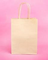 paper bag with handles for shopping on pink background photo