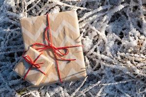 Cajas de regalo atadas con hilo rojo sobre la hierba helada, felicitación y celebración de las fiestas.