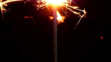 de cerca, brilla intensamente con destellos de luz. las chispas de los fuegos artificiales. en medio de una atmósfera oscura. video