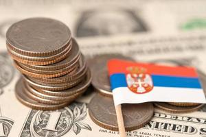 Stack of coins with Serbia flag on US dollar banknotes background. photo