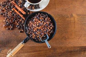 Top view of coffee beans roasted in a pan and a coffee cup. photo