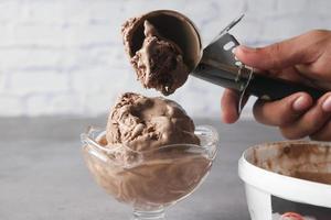 mano recogiendo helado con una cuchara de un tazón foto