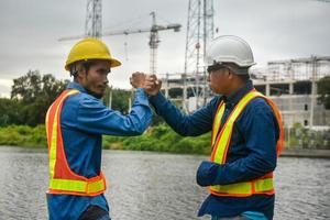 Ingeniero de trabajo en equipo y apretón de manos de empresario en el sitio de construcción foto