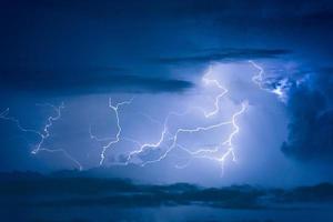 Thunder storm lightning strike on the dark cloudy sky background at night. photo