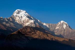 Annapurna South mountain peak with blue sky background in Nepal photo