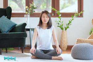 Hermosa mujer asiática mantén la calma y medita mientras practica yoga en casa para un estilo de vida saludable