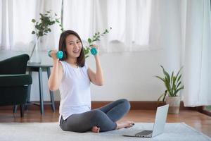 Hermosa mujer asiática mantenerse en forma haciendo ejercicio en casa para un estilo de vida saludable foto