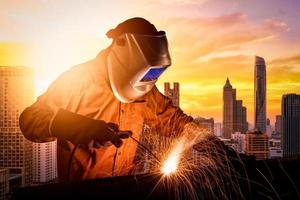 Trabajador industrial soldando estructura de acero para proyecto de construcción de infraestructura. concepto de fotografía para la industria de la construcción y trabajos de ingeniería. foto