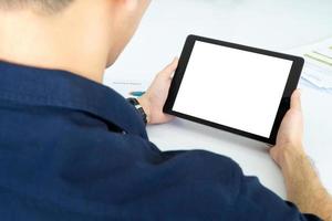 Back view of Business man using tablet with black screen in office. Photo design with copy space for mock up for video conferencing with colleagues via internet technology at home office.