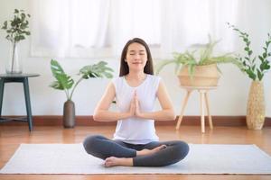 Hermosa mujer asiática mantén la calma y medita mientras practica yoga en casa para un estilo de vida saludable