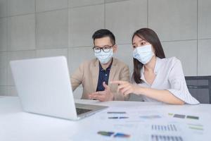 Empleados comerciales que usan máscara durante el trabajo en la oficina para mantener la higiene y seguir la política de la empresa. Prevención durante el período de epidemia de coronavirus o covid19. foto