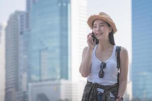 Beautiful asian solo tourist woman smiling and enjoy taking via mobile phone in city downtown. Vacation travel in summer. photo