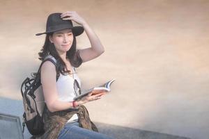 hermosa mujer asiática turista en solitario leyendo la guía de viajes en busca de lugares turísticos para turistas. viajes de vacaciones en verano. foto