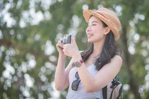 Hermosa mujer turista asiática en solitario disfruta tomando fotos con una cámara retro en un lugar turístico. viajes de vacaciones en verano.