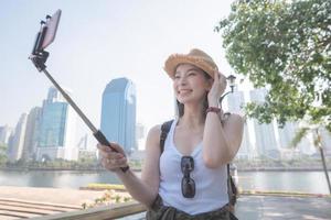 Beautiful asian tourist woman taking selfies on a smartphone in urban city downtown. Vacation travel in summer. photo